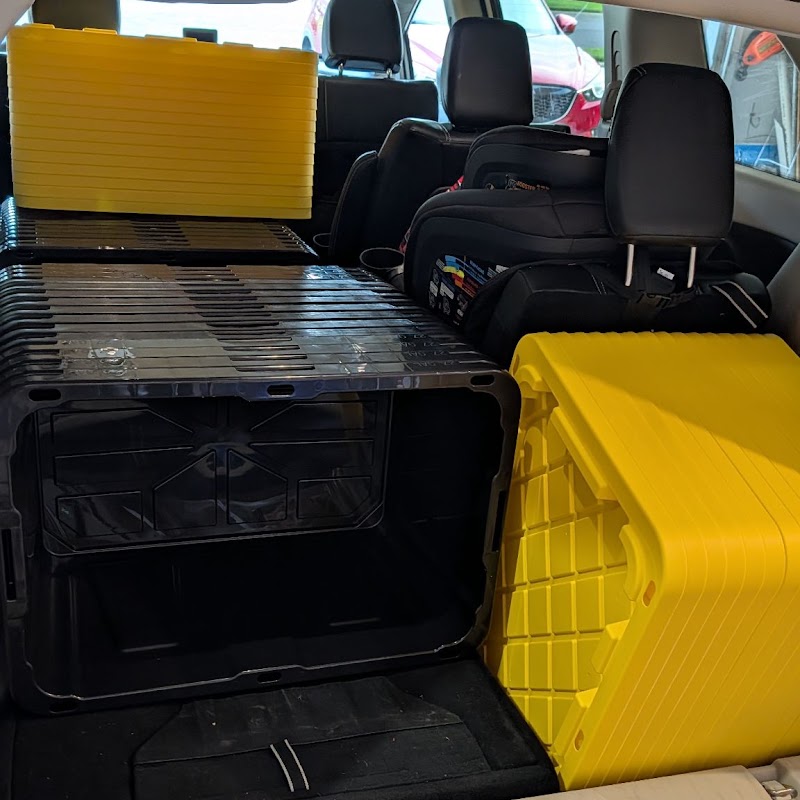 The back of an SUV loaded with stacked black-and-yellow moving totes, ready for delivery